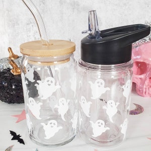 May include: Two clear glass water bottles with ghost designs. One bottle has a bamboo lid and a straw. The other bottle has a black lid with a built-in straw.