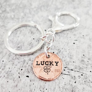 Peut inclure: Un porte-clés argenté avec un sou de 1986 attaché. Le sou porte les mots "LUCKY" et un trèfle à quatre feuilles gravés.