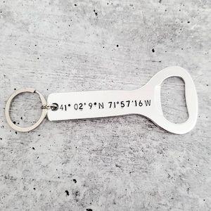 May include: Silver bottle opener keychain with a key ring and engraved coordinates: 41° 02' 9.9"N 71° 57' 16"W.