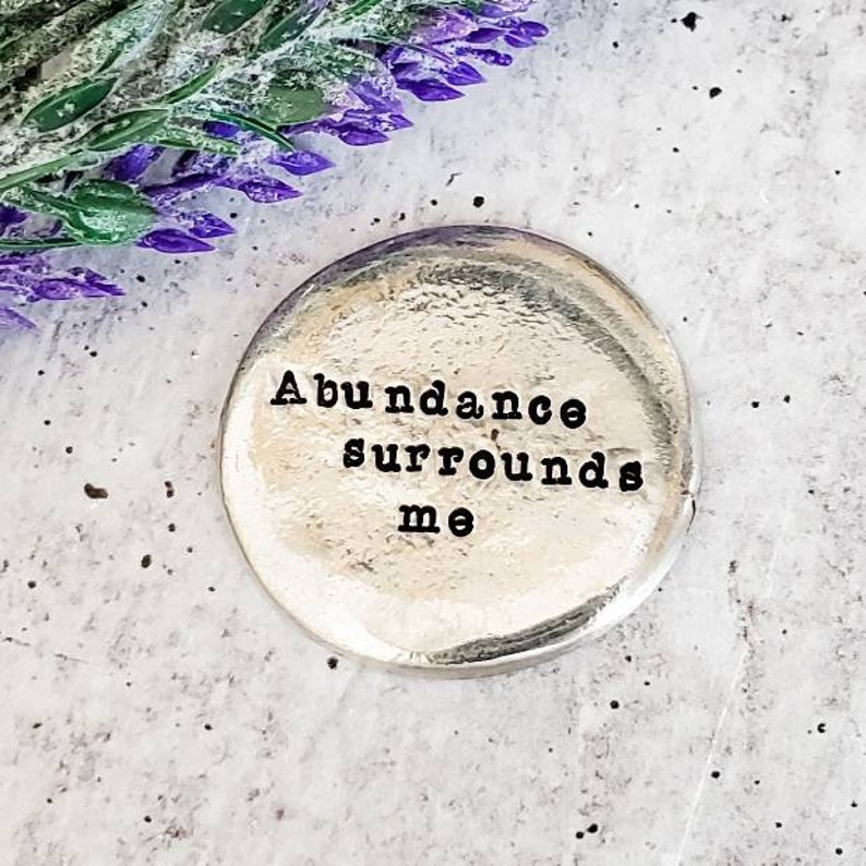 Peut inclure: Un jeton rond en argent avec les mots "L'abondance m'entoure" grav&eacute;s dessus.