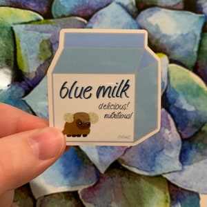 May include: A blue milk carton sticker with a brown and white furry creature with horns. The sticker reads 