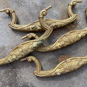 May include: A white ceramic mug with a black handle and the text "But First, Coffee" in a bold, black font. The mug is set against a neutral background, highlighting its simple design.