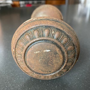 May include: Close-up of a vintage, rusty, metal door knob with a decorative, circular design.