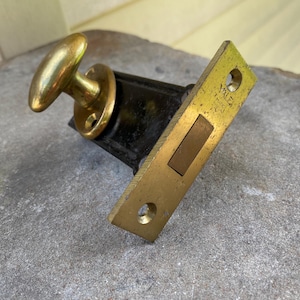 May include: A vintage Yale door latch mechanism featuring a polished brass knob and a rectangular brass faceplate with two screw holes. The central body is finished in black metal, and the faceplate is engraved with the Yale brand name.