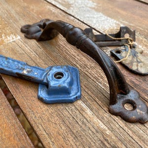 May include: Two antique door handles, one black with a decorative design and the other blue with a square base.