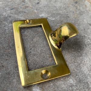 May include: A rectangular brass drawer pull with a curved handle. The pull has a polished finish and two screw holes. The hardware is designed for furniture and cabinets.