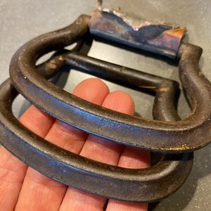 May include: A pair of antique metal handles with a copper finish. The handles are made of cast iron and have a rustic look. They are perfect for adding a vintage touch to any project.