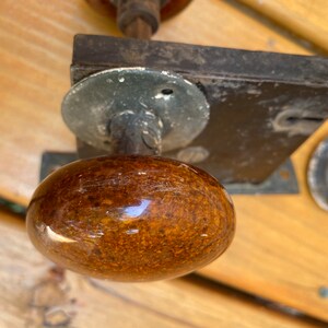 May include: Close-up of a brown ceramic door knob with a metal base and a keyhole. The knob is attached to a black metal door plate.