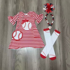 Peut inclure: Une robe rayée rouge et blanche sur le thème du baseball avec un sac à main, un nœud, un collier et des chaussettes assortis. La robe présente un graphisme de baseball et des manches à volants. Les chaussettes ont des accents rouges et des coutures de baseball.