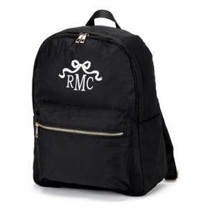 May include: Black backpack with a white embroidered bow and the initials "RMC".