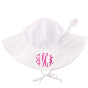 May include: White sun hat with a pink monogrammed "S.H." on the front. The hat has a wide brim and a chin strap.
