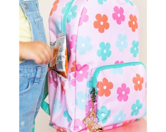 May include: A pink backpack with a floral pattern featuring pink, orange, and teal flowers. The backpack has a front pocket and a zipper closure. A gold butterfly charm hangs from the zipper pull.