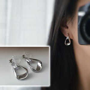 Invisible resin clip-on earrings with rectangular and irregular triangular zircons in silver. Comfortable ear clips.