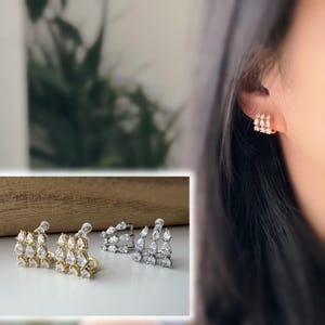 Eleganti orecchini pendenti con clip in zirconi in oro/argento. Un design raffinato per un tocco di glamour e brillantezza.