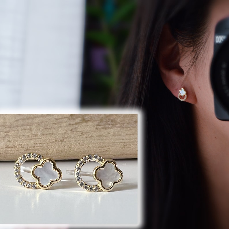 May include: A pair of gold earrings with a white clover-shaped design and clear crystal accents.