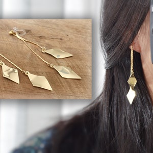 Op de afbeelding: Gouden oorhangers met drie diamantvormige bedels. De oorbellen zijn van het clip-on type.