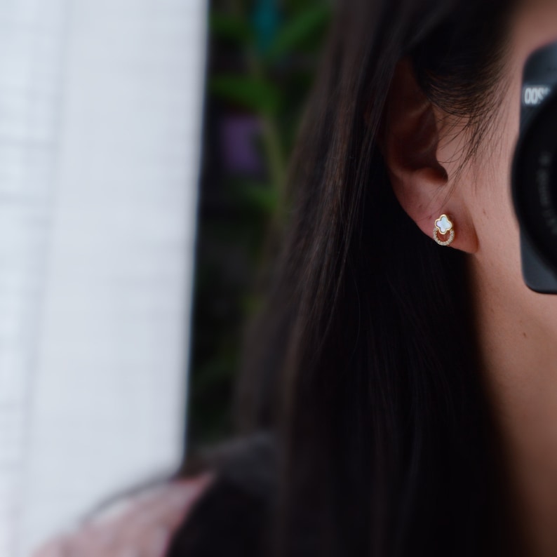 May include: A pair of gold earrings with a white stone in the center and a circle of small stones around the edge.