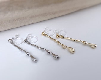 Puede incluir: Tres pares de pendientes de clip con un diseño de líquido goteando. Los pendientes están disponibles en oro, plata y transparente.