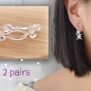 Peut inclure: Deux paires de dos d'oreille en plastique transparent avec de petits strass transparents. Les dos d'oreille sont conçus pour maintenir les boucles d'oreilles pendantes en place.  2 paires.