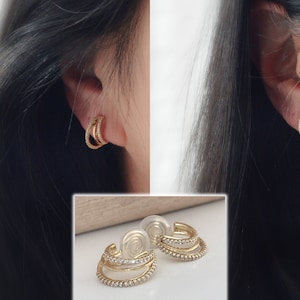 Comfortable U-shaped clip-on earrings with a spiral design and triple zircon rings. Delicate, comfortable 18K gold-plated ear clips.