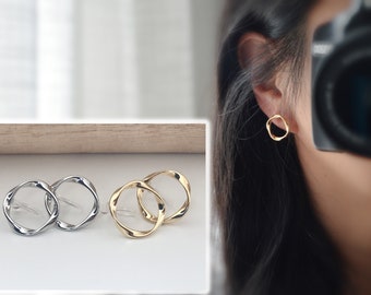 Brincos de pressão invisíveis em resina, formato de círculo torcido, cor prata/dourada. Joias confortáveis e minimalistas para o dia a dia.