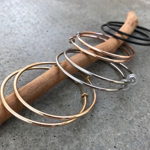 Op de afbeelding: Een set van vier hoepeloorbellen in goud, zilver en zwart. De oorbellen zijn gerangschikt op een houten tak.