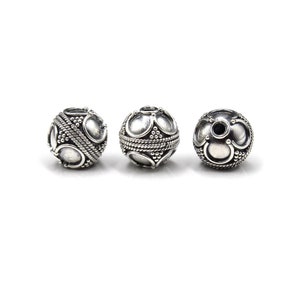 May include: Three silver-colored, round beads with intricate designs. Each bead features a pattern of oval shapes, small dots, and a rope-like texture around the center. The beads are displayed against a white background.