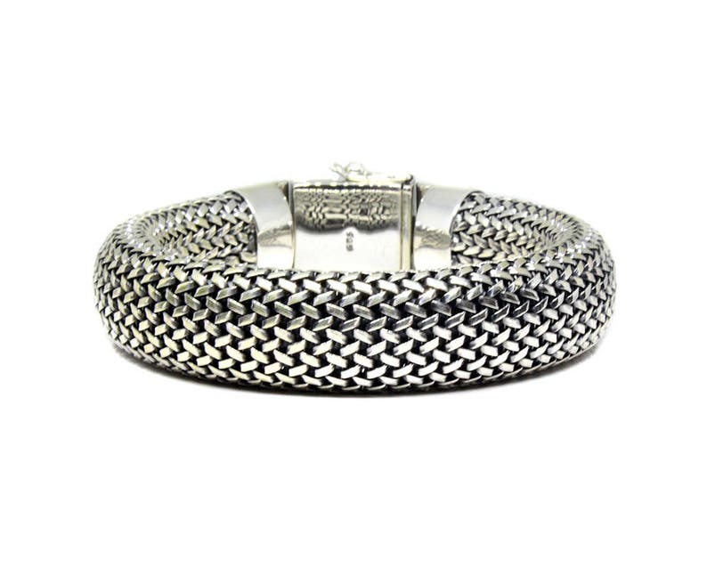 May include: A silver bracelet with a woven chain design.