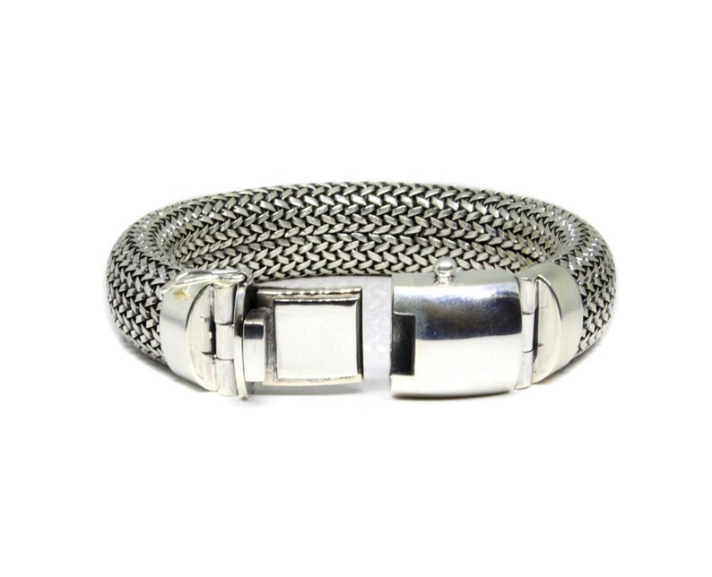 May include: A silver bracelet with a woven chain design and a silver clasp.