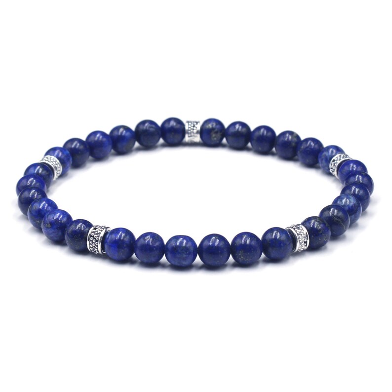 May include: A blue lapis lazuli beaded bracelet with silver accents. The bracelet is made with round beads and has a simple design.
