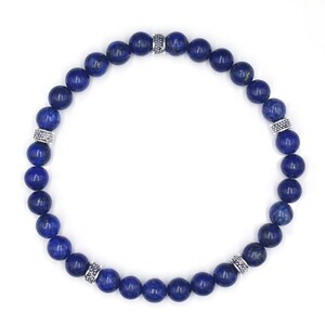 May include: A blue lapis lazuli beaded bracelet with silver accents. The bracelet is made of round beads and has a simple design.