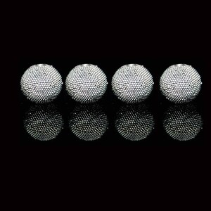May include: Four spherical objects with a textured, studded surface are arranged in a row. The objects are silver in color and reflect light, creating a sparkling effect. The objects are set against a black background.