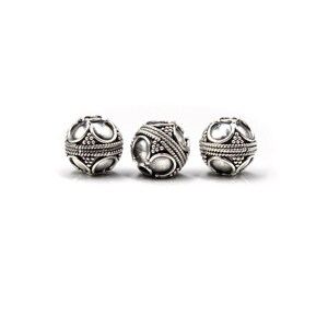 May include: Three silver-colored, spherical beads. Each bead features a pattern of raised, oval shapes and small dots, with a band of twisted metal around the center. The beads are displayed against a white background.