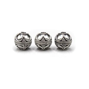 May include: Three silver-colored, spherical beads with an ornate design. Each bead features a crown-like top, a textured band, and a detailed lower section. The beads are displayed against a white background, highlighting their intricate details.