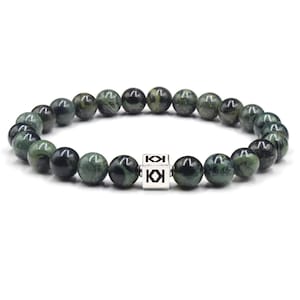 Op de afbeelding: Een armband met donkergroene en zwarte bolvormige kralen. Een zilveren kubus met de letters "KK" is gecentreerd op de armband. De kralen zijn aan elkaar geregen om een cirkelvorm te vormen.