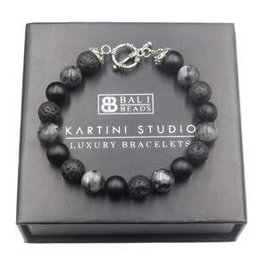 May include: Black bracelet with lava rock, black onyx, and moonstone beads. The bracelet has a silver toggle clasp and is packaged in a black box with the text "Bali Beads Kartini Studio Luxury Bracelets".