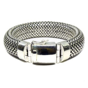 May include: A silver bracelet with a woven chain design and a clasp closure.