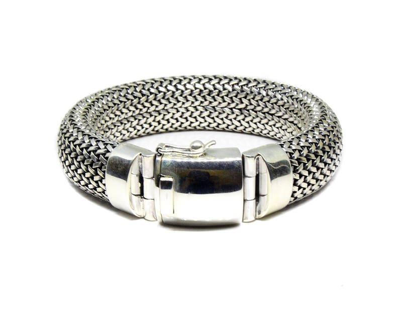 May include: A silver bracelet with a woven chain design and a clasp closure.