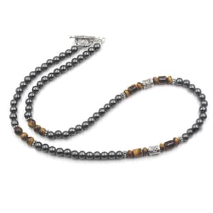 Puede incluir: Un collar de cuentas de hematites negro y ojo de tigre con detalles plateados. El collar tiene un cierre de palanca.