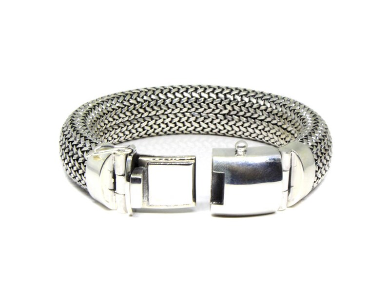 May include: A silver bracelet with a woven chain design and a clasp closure.