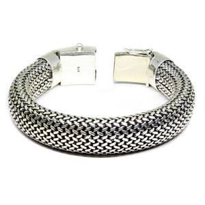 May include: A silver bracelet with a woven design. The bracelet has a clasp closure.