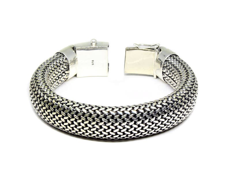May include: A silver bracelet with a woven design. The bracelet has a clasp closure.