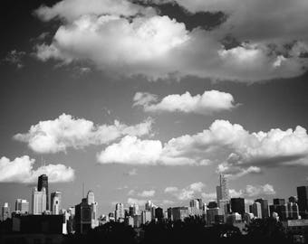 Puede incluir: Una fotografía en blanco y negro de un horizonte urbano con edificios altos y un cielo nublado.