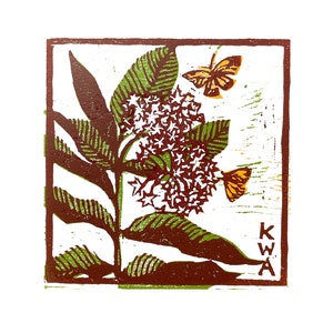 以下が含まれることがあります： 茶色と緑色のリノカット版画で、オレンジ色の蝶が2匹ついた花が咲いた植物が描かれている。版画は茶色の枠で囲まれ、右下に「KWA」と署名されている。