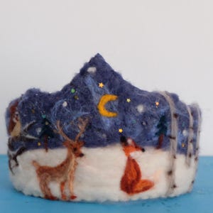 May include: A felt crown depicting a blue night sky scene, with a crescent moon, stars, a deer, a fox, and a snowy landscape.