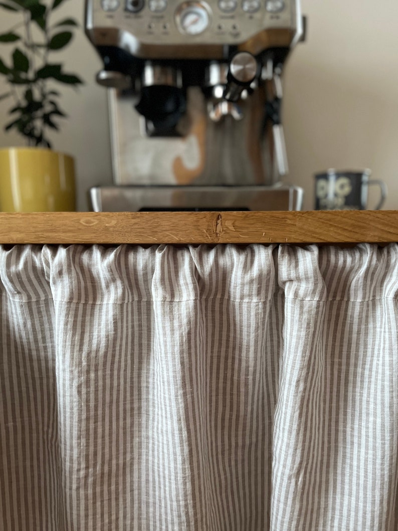 beige stripe linen curtain panel is gathered on a pole to cover space under  kitchen work top