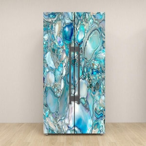 May include: A refrigerator with a custom wrap featuring a blue, white, and gray abstract design. The pattern resembles a collection of stones or gems, with varying shades of blue and white. The refrigerator has dark gray handles.