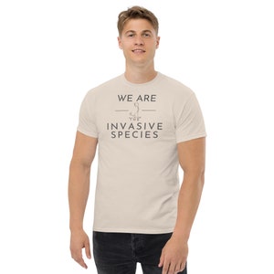 Könnte beinhalten: Ein beiges T-Shirt mit einer schwarzen Grafik, auf der "We are the invasive species" steht.