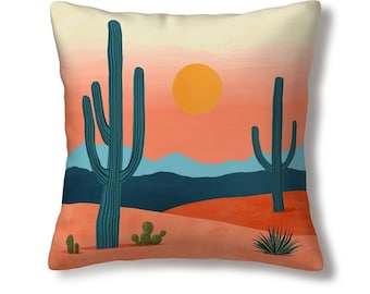 Puede incluir: Cojín cuadrado con un diseño de paisaje desértico. El cojín presenta una vibrante puesta de sol naranja, cactus azules y un sol amarillo. El diseño incluye una escena desértica con montañas y varias plantas del desierto.