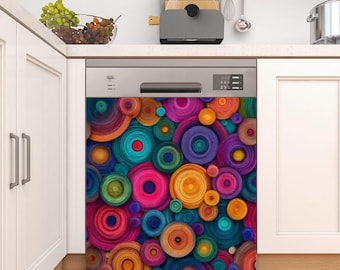 Puede incluir: Un lavavajillas con un diseño abstracto y colorido. El panel frontal presenta un patrón de círculos superpuestos en tonos de rosa, morado, azul, verde y amarillo. El electrodoméstico de cocina está colocado contra armarios y una encimera blancos.